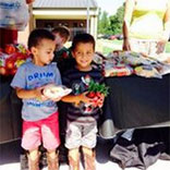 Two young boys holding radishes and learning about healthy food choices as part of the Food for Kids program managed by the Community Food Bank of Eastern Oklahoma.